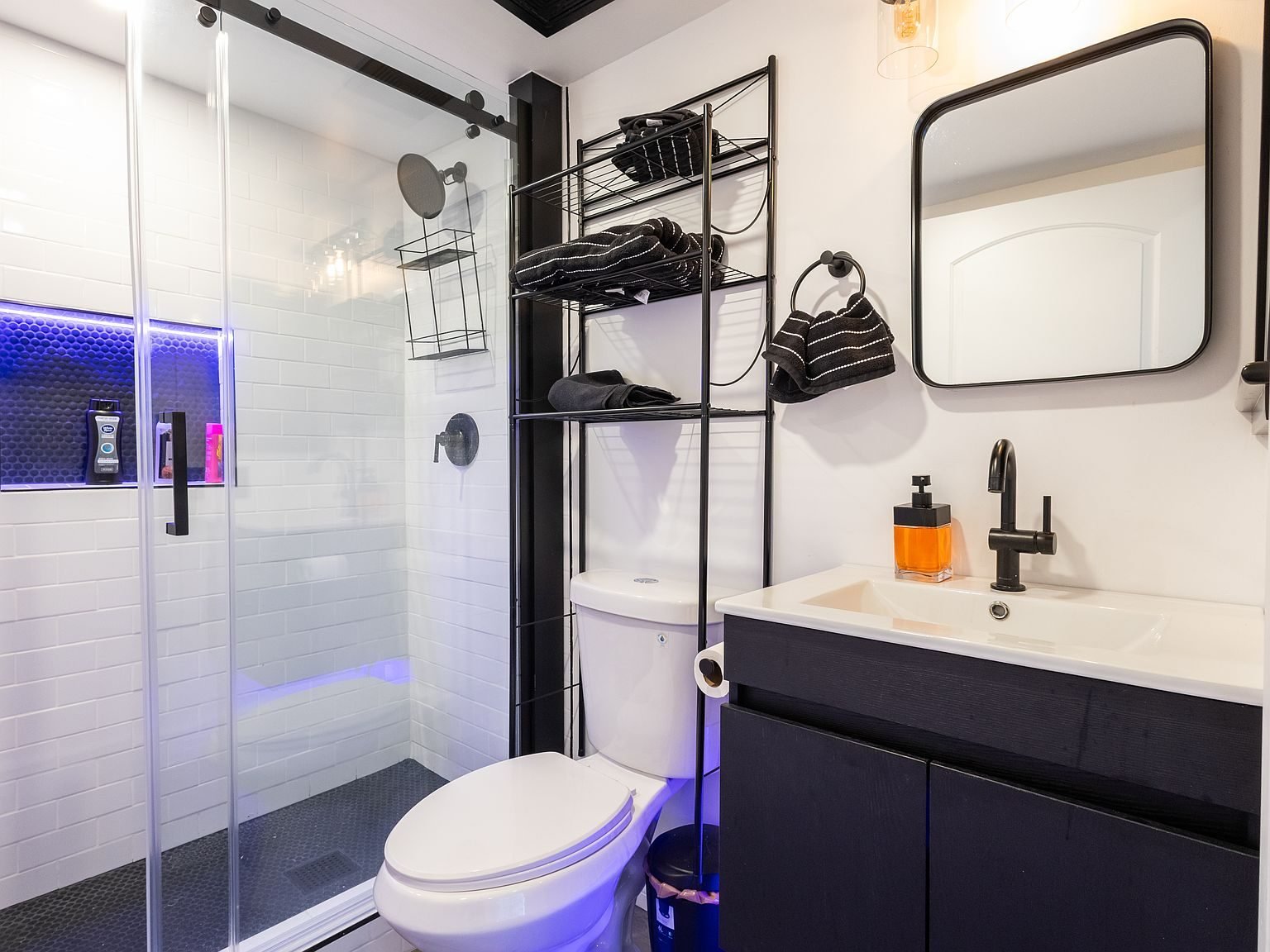 Remodeled bathroom with glass shower, dark vanity, and black fixtures