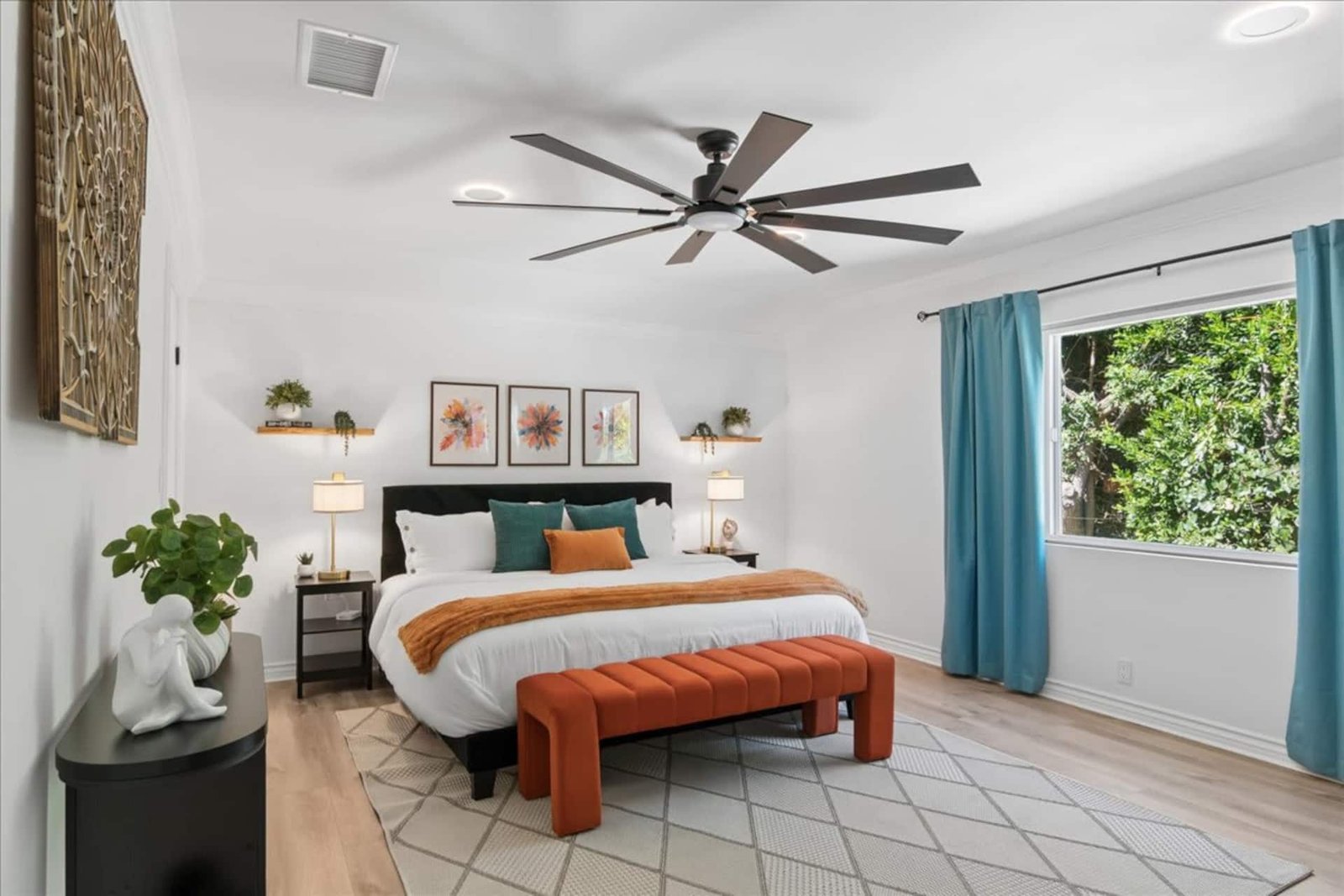 Bedroom with an orange upholstered bench at the foot of the bed and a ceiling fan