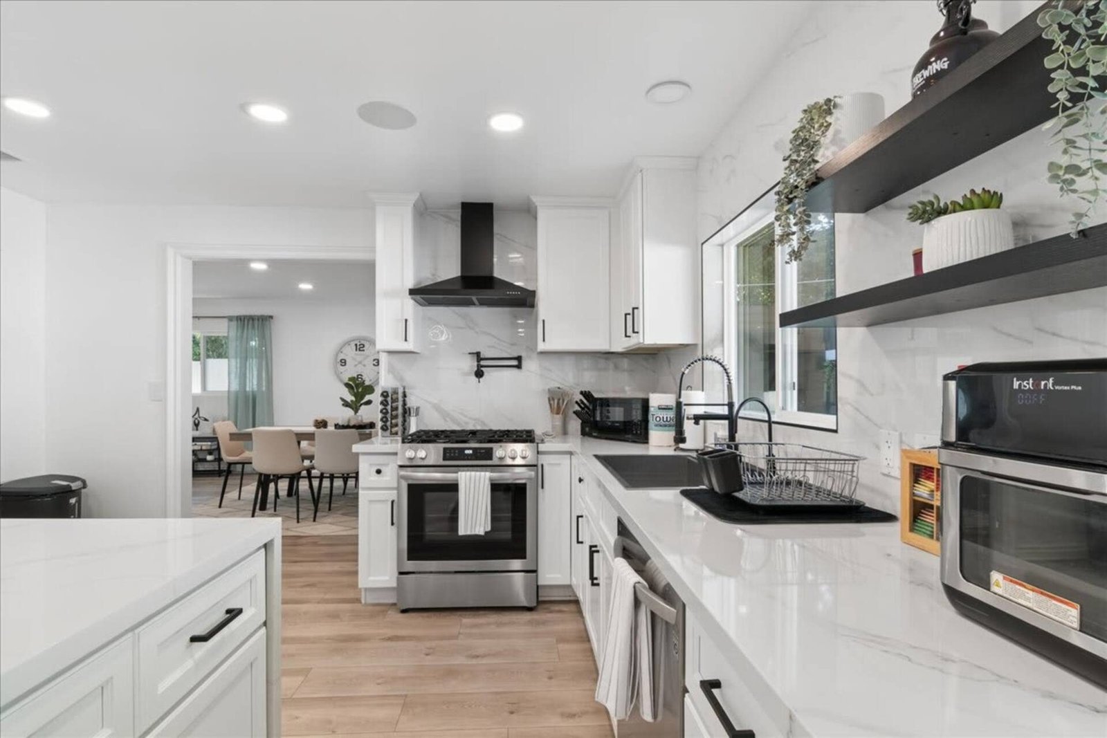 White kitchen with gas range, open shelving, and a large island